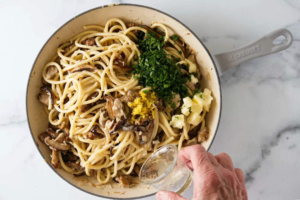 Mixing ingredients in a skillet for pasta with wild mushrooms.