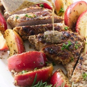 Pouring sauce over a braised pork tenderloin with apples.