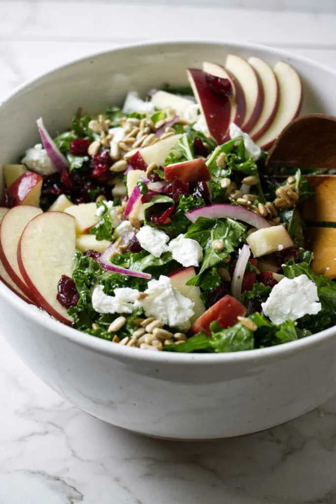 A kale apple cranberry salad in a large bowl.