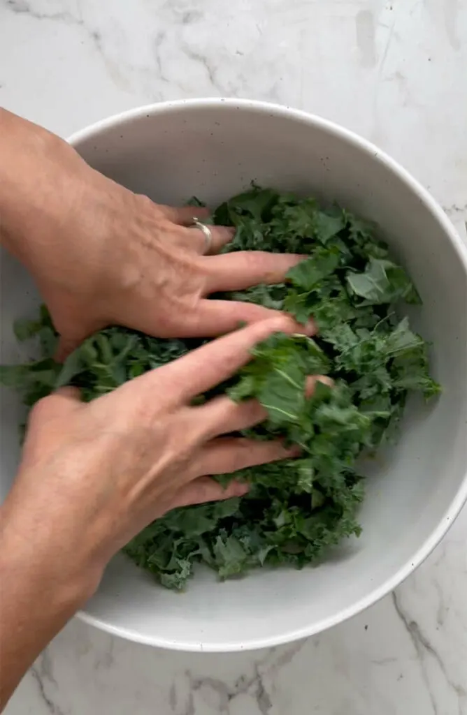 Massaging kale for salad in a bowl.