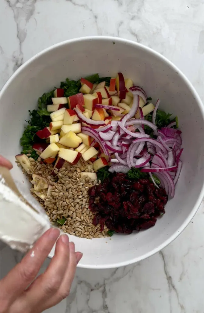 Making a recipe for kale salad with cranberries.