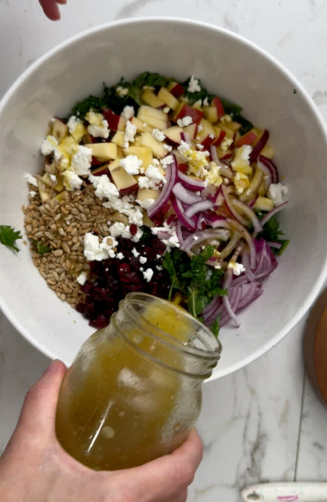 Adding vinaigrette to a kale and cranberry salad.