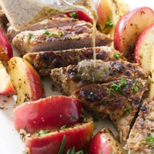 Pouring sauce over a cider braised pork tenderloin with baked apples.