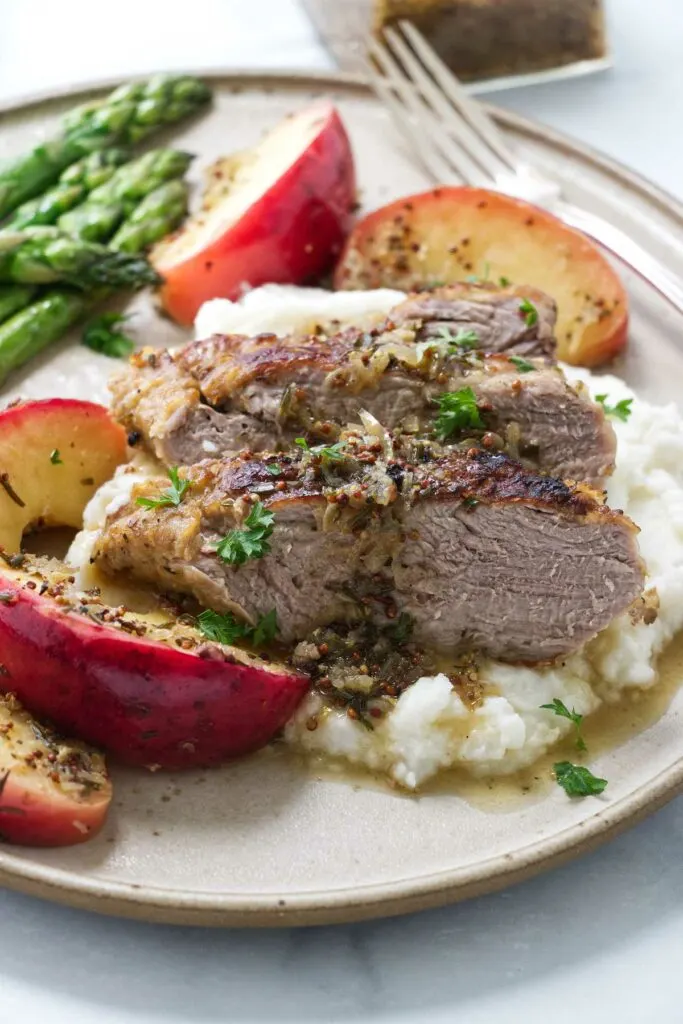 Apple cider braised pork tenderloin on a plate.