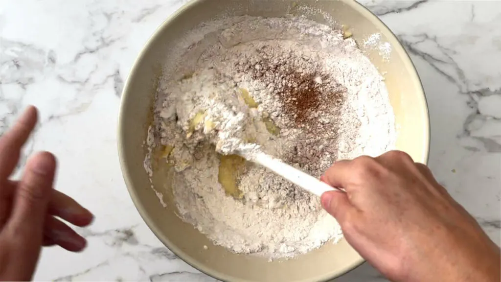 Folding in the flour mixture to make apple bread.