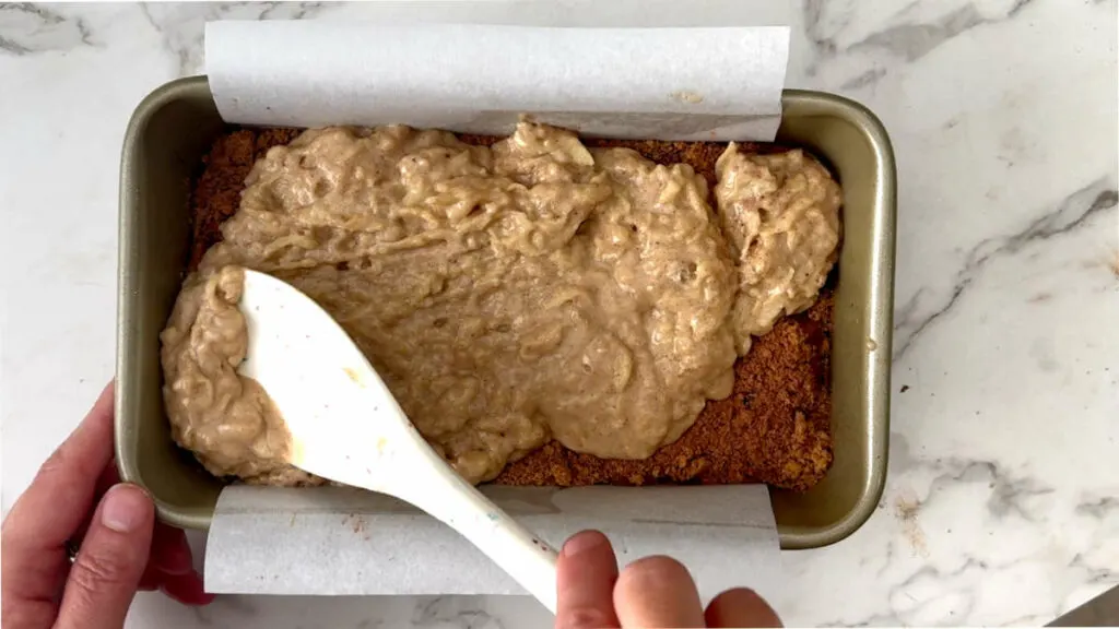 Spreading apple bread batter in a loaf pan.