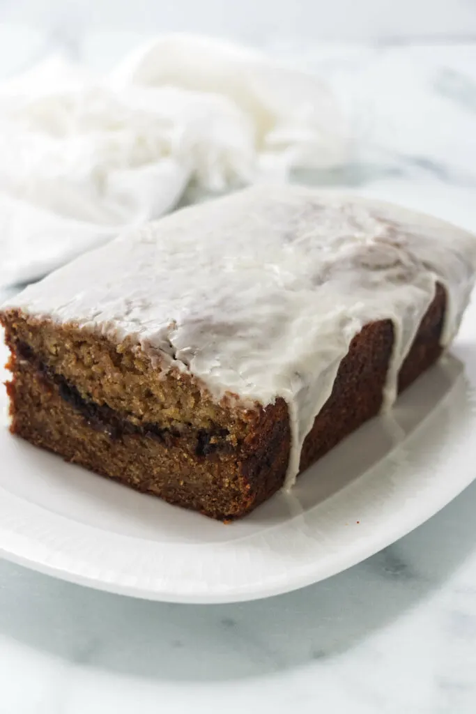 An apple loaf quick bread with maple icing on a plate.