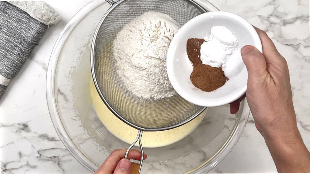 Adding flour and spice for a spiced pear cake.