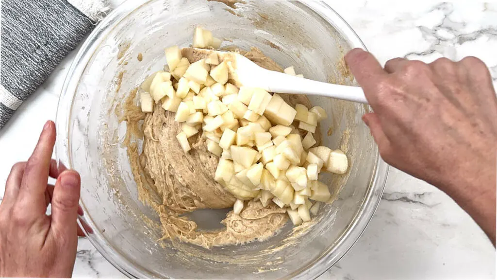 Folding diced pears into a pear coffee cake batter.