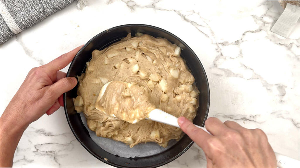 Spreading pear cake batter in a pan.