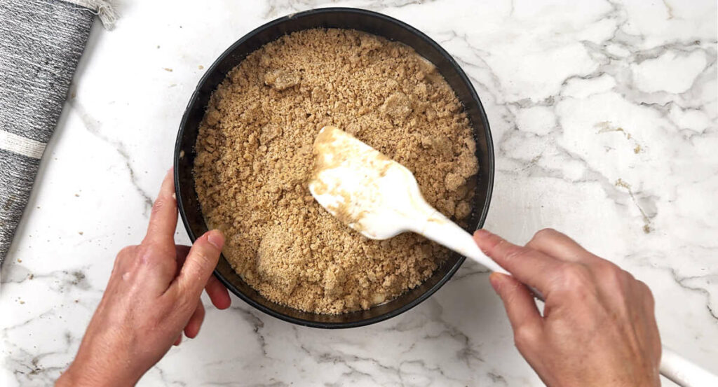 Spreading crumble topping on a pear cake.