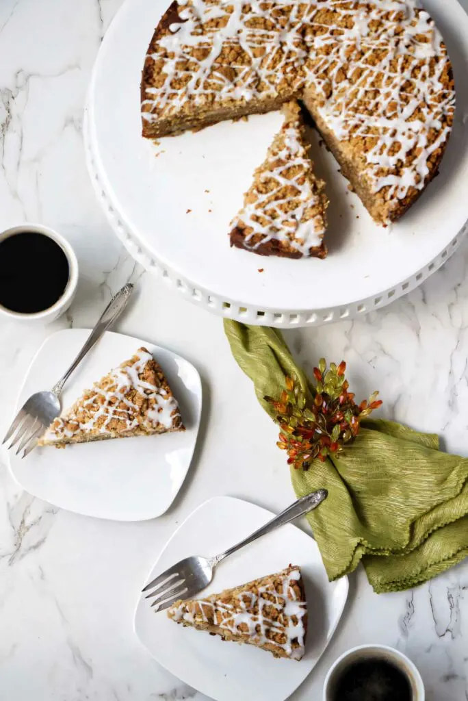 Pear crumb cake on a plate with two slices next to it.