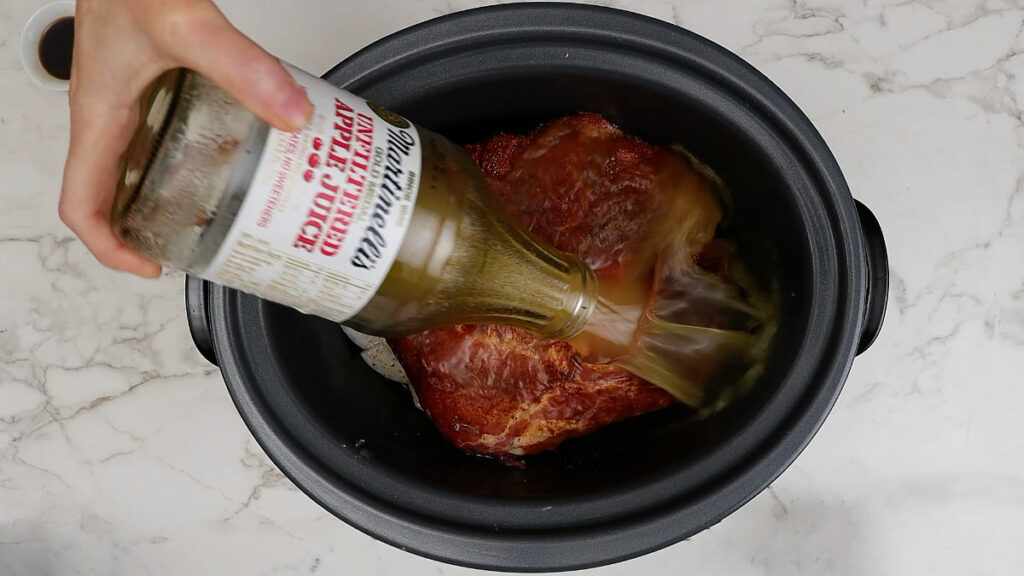 Adding apple juice to the slow cooker barbecue pulled pork.