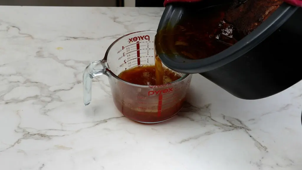 Pouring the excess juices off the slow cooker bbq pulled pork.