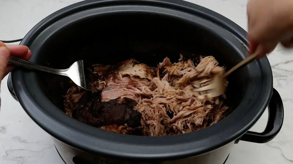 Shredding pork butt for a bbq pulled pork recipe slow cooker.