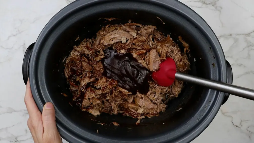 Adding sauce to the barbecue pulled pork recipe.