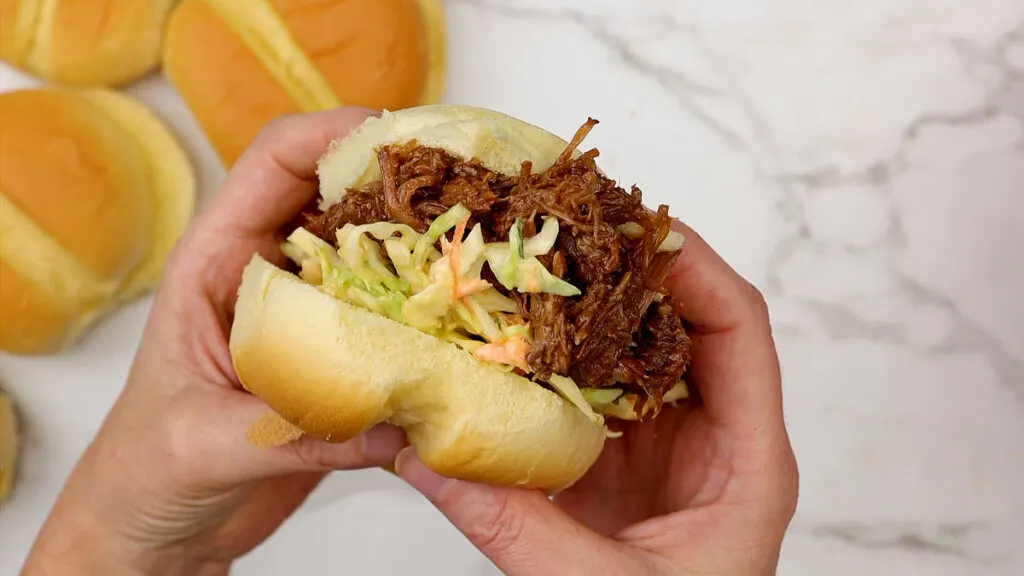 Serving crockpot bbq pulled pork on buns with coleslaw.