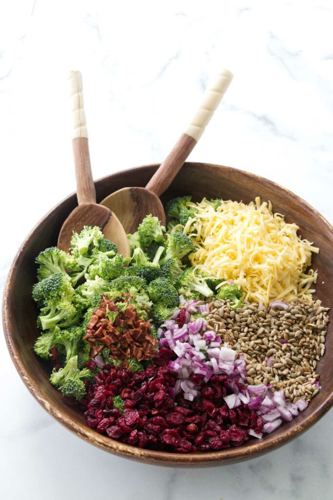 Salad ingredients in a bowl with salad utensils.