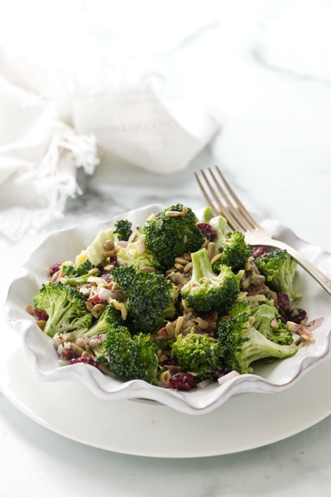 A serving of broccoli cranberry salad in a dish and a fork alongside.