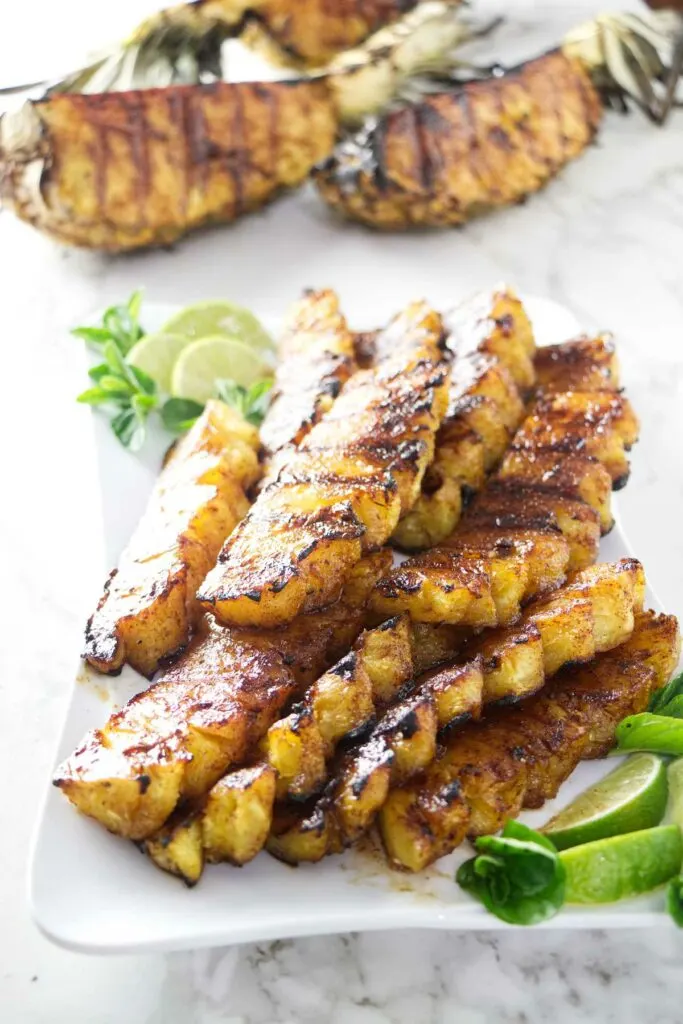 A serving platter with grilled pineapple and lime slices.