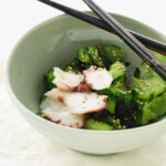 A dish of Japanese cucumber salad with octopus and sesame seeds.