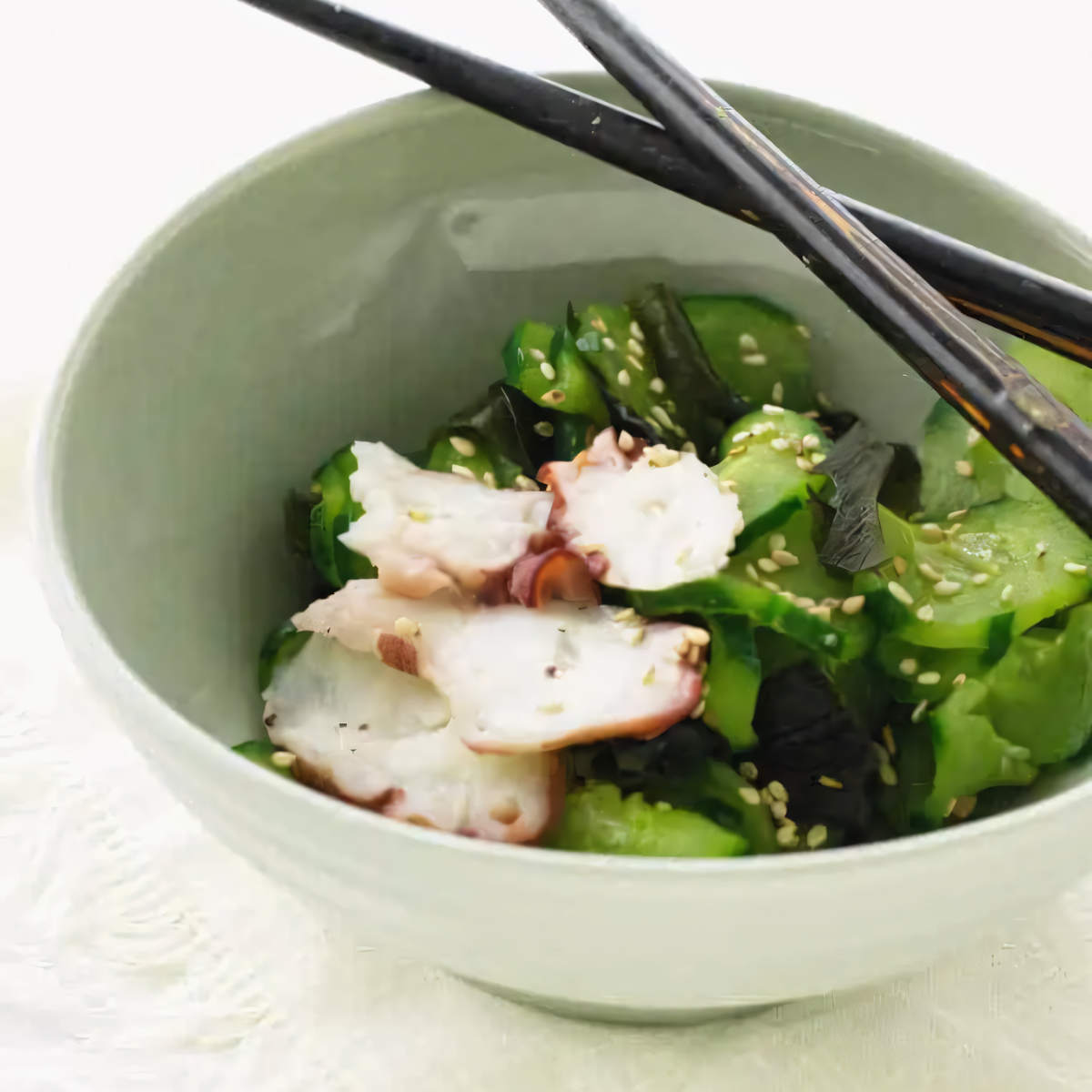 A dish of Japanese cucumber salad with octopus and sesame seeds.