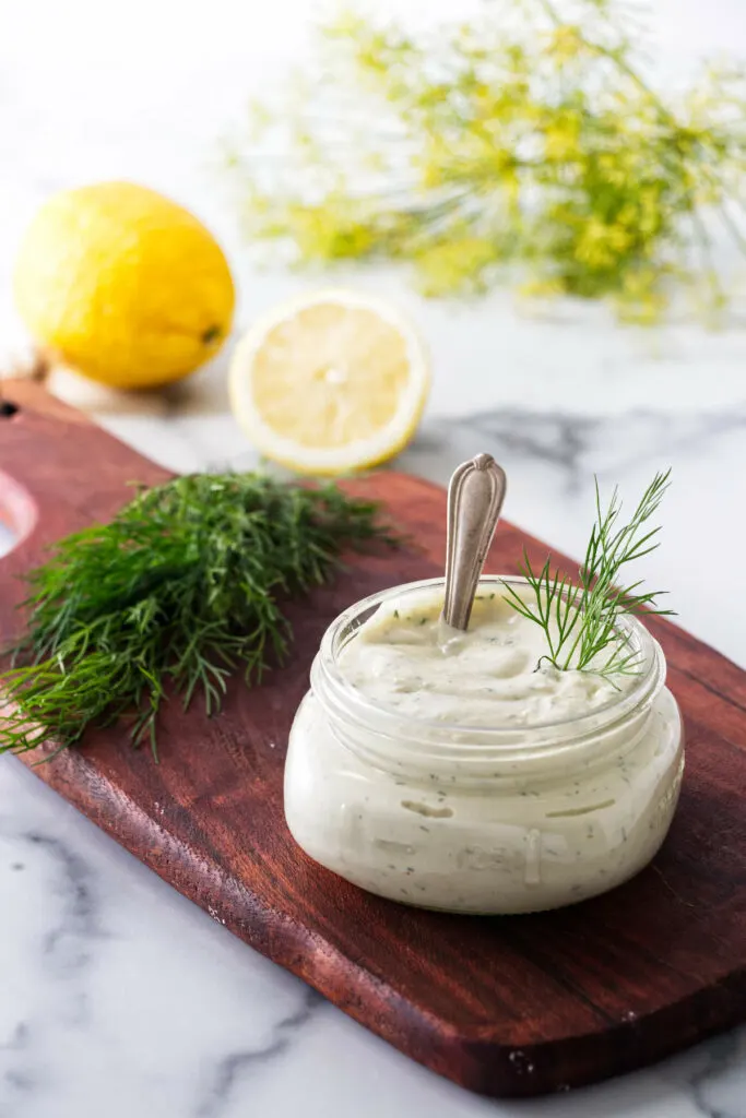 A dill sprig in a jar of lemon garlic and dill aioli.