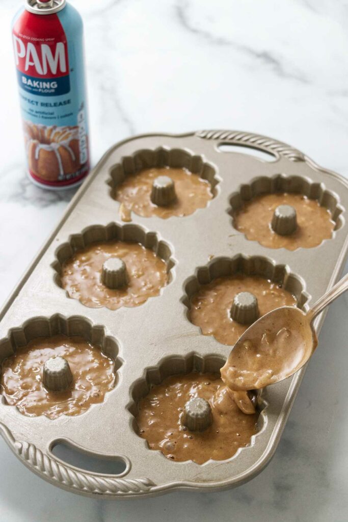 Adding apple cake batter to a mini bundt pan.