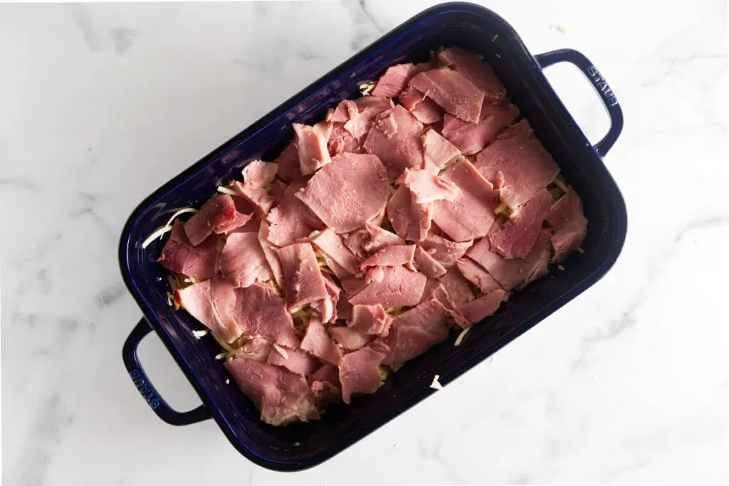 Placing a layer of ham in the baking casserole.