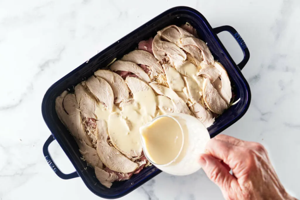 Adding the milk and cream mixture to the casserole.