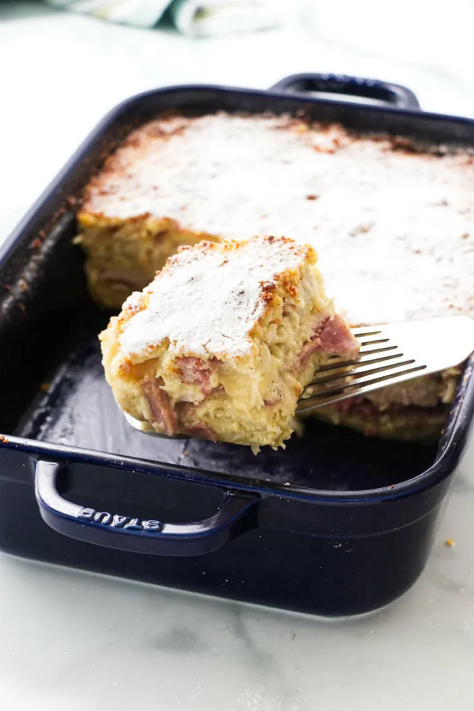 A spatula lifting a slice of a ham and turkey casserole.