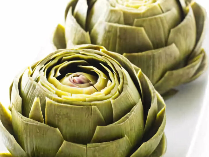 Several steamed artichokes on a serving platter.