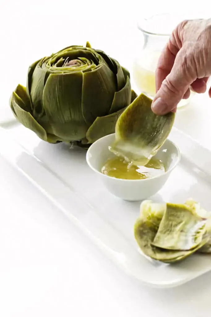 Dipping leaves of freshly steamed artichokes into melted butter.