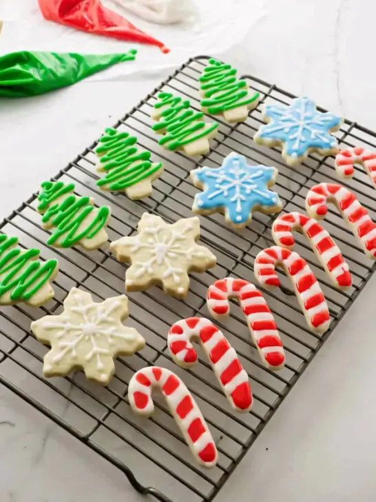 Several decorated Christmas cut out sugar cookies on a wire rack.