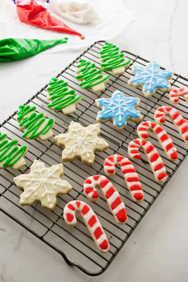 Several decorated Christmas cut out sugar cookies on a wire rack.