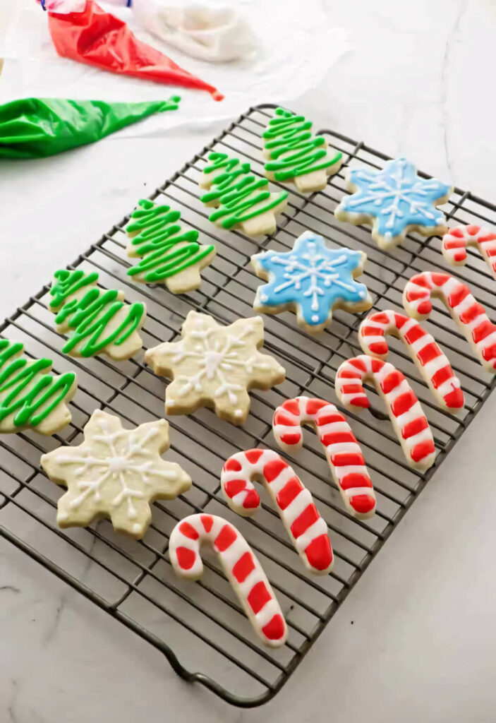 Several decorated Christmas cut out sugar cookies on a wire rack.