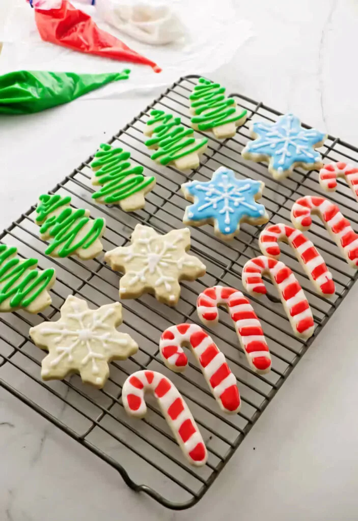 Several decorated Christmas cut out sugar cookies on a wire rack.