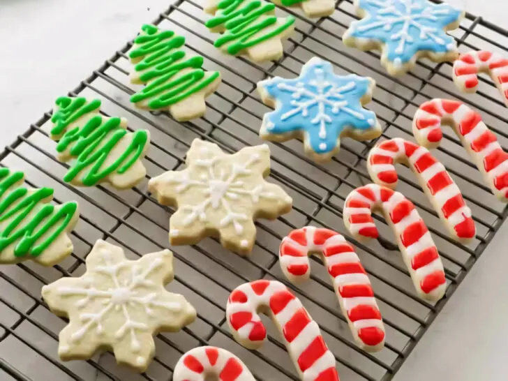 Several decorated Christmas cut out sugar cookies on a wire rack.