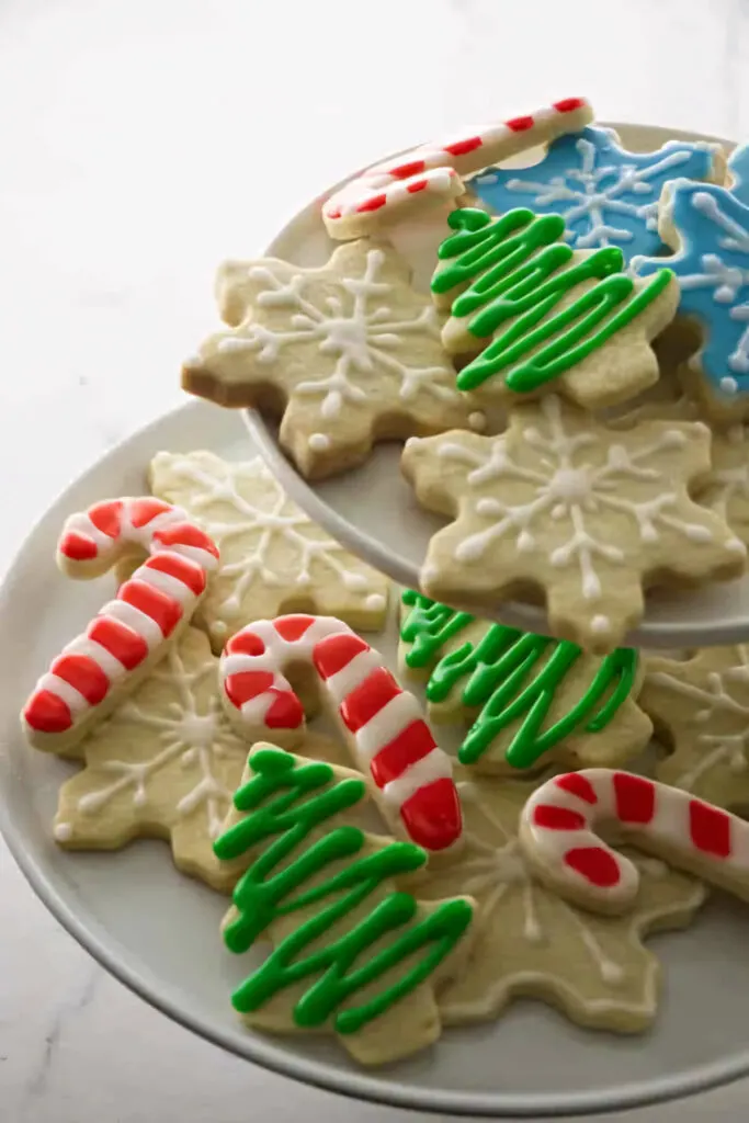 A tiered platter of Christmas cut out cookies decorated with royal icing.