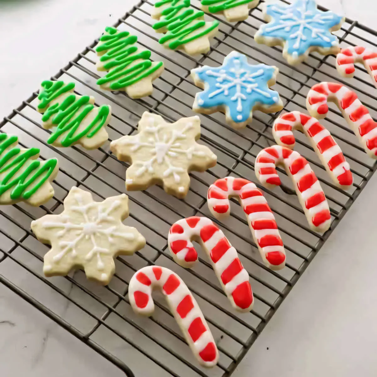 Christmas sugar cookies decorated as trees, snowflakes, and candy canes.