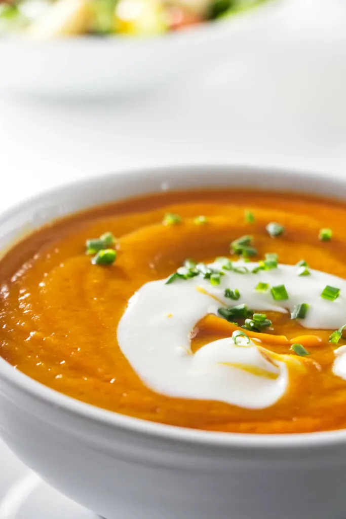 Carrot soup in a bowl with a dollop of sour cream.