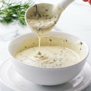 Scooping creamy tarragon sauce out of a bowl.