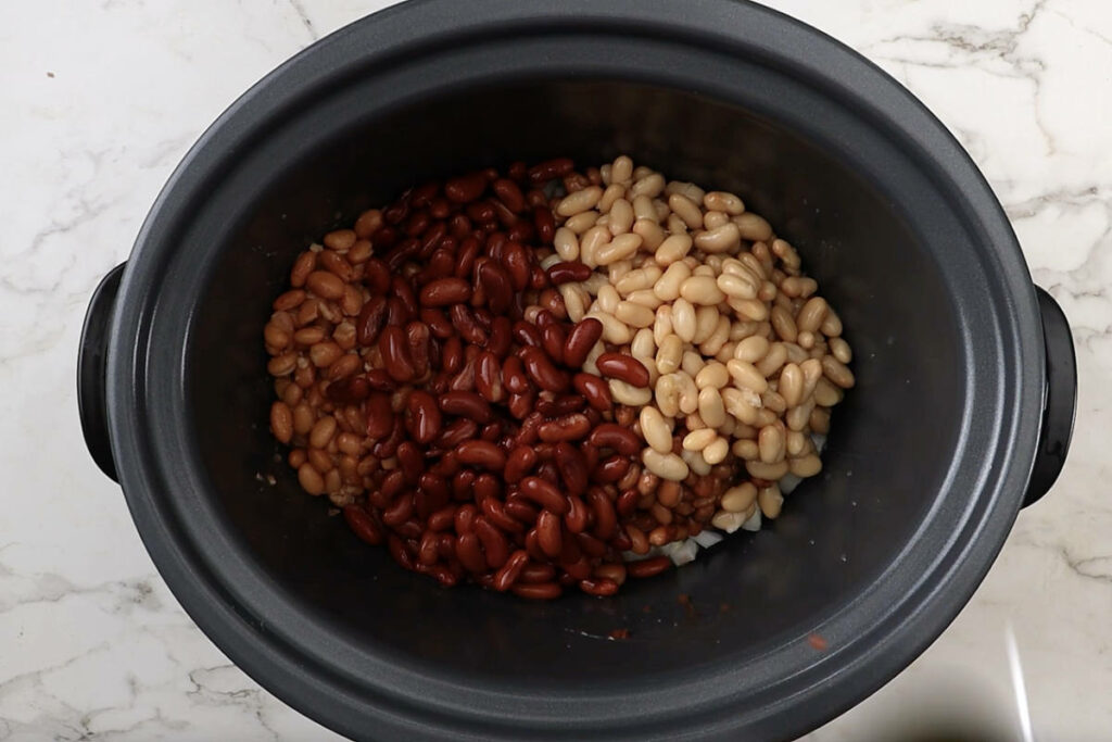 Canned beans added to a crockpot.