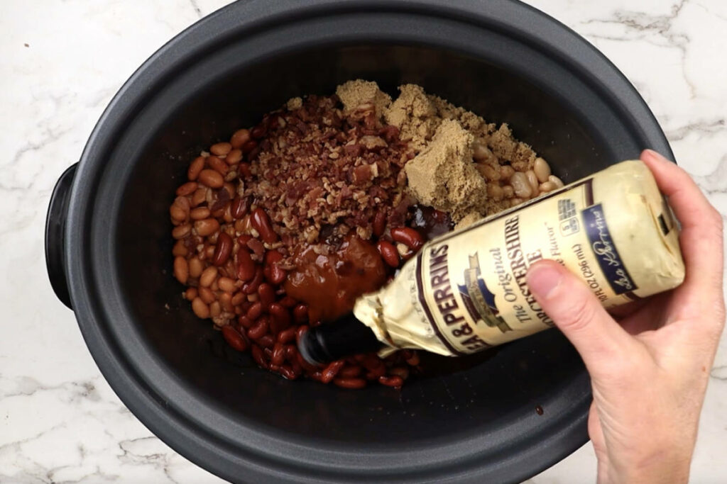 Adding Worcestershire sauce to the slow cooker.