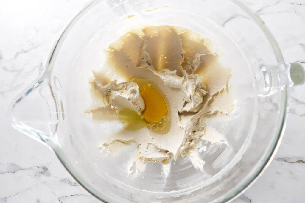 Adding eggs to the creamed butter and sugar mixture to make cut out sugar cookies for Christmas.