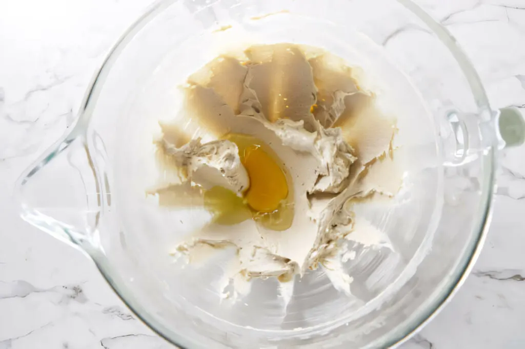 Adding eggs to the creamed butter and sugar mixture to make cut out sugar cookies for Christmas.