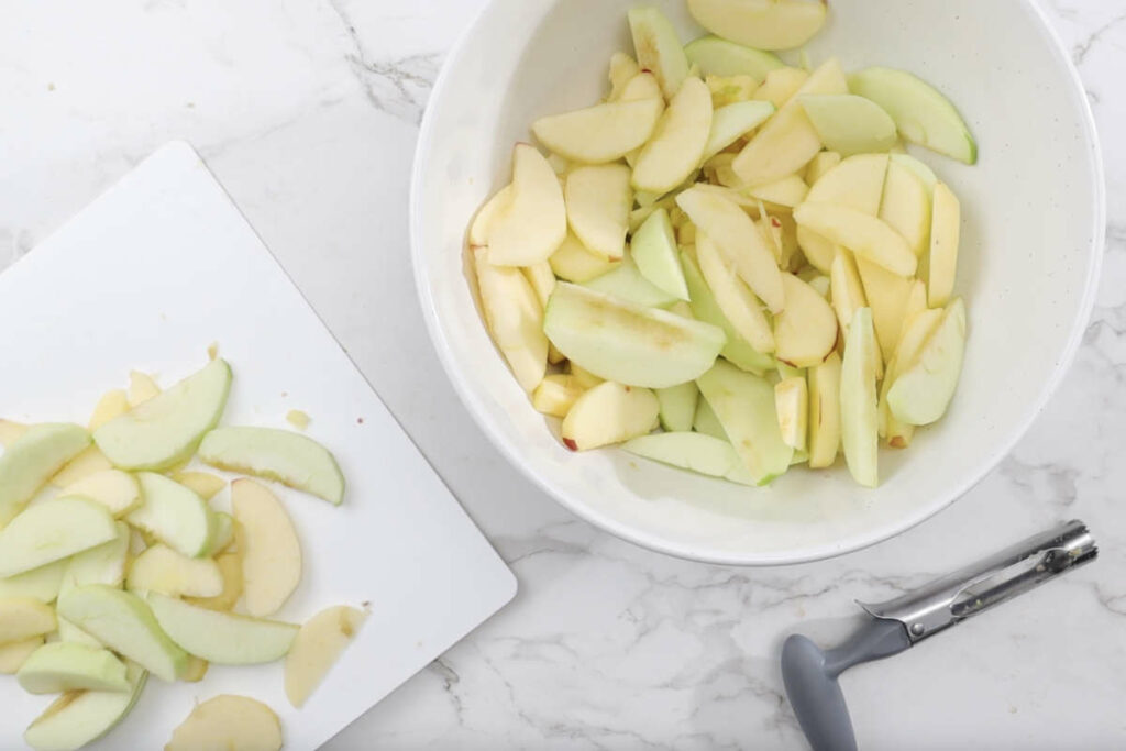 Tossing apple slices in a bowl with lemon juice.