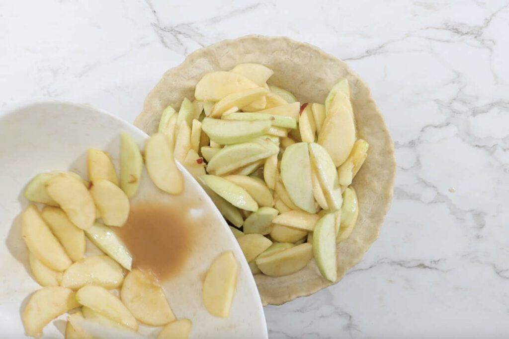 Adding the apple mixture to the pie.