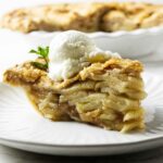 A slice of deep-dish apple pie with a scoop of ice cream.