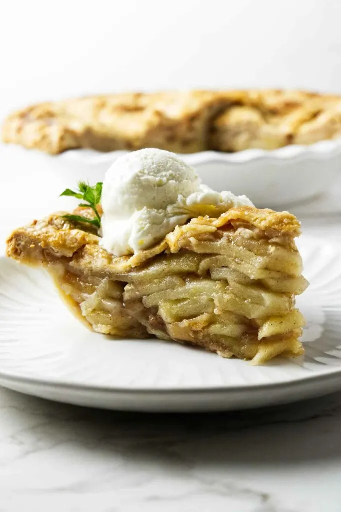 A slice of deep-dish apple pie with a scoop of ice cream.